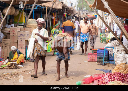 Portiere di mercato portano pesanti sacco presso il mercato all'aperto in Tiruchirappalli, Tamil Nadu, India Foto Stock