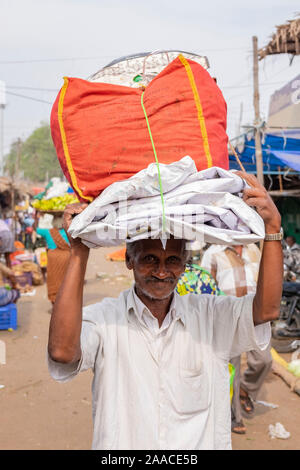 Il vecchio uomo portante avvolto il pacco di plastica sulla sua testa al mercato all'aperto in Tiruchirappalli, Tamil Nadu, India Foto Stock