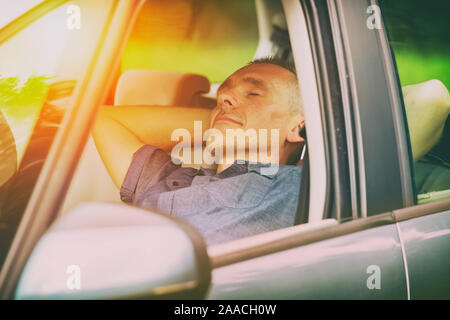 Uomo dorme in auto prima della successiva parte del viaggio Foto Stock