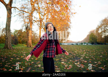 Felice giovane donna asiatica girarsi nel parco. Stile di vita all'aperto RF con colori autunnali. Novembre 2019 Foto Stock