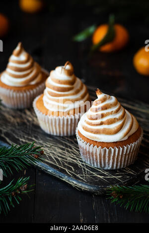 Tortini di agrumi con riccioli di limone e un cappello da Swiss meringa. Il dessert sul nuovo anno di tabella. Foto Stock