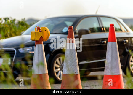 Vista tramonto uk servizi autostradali roadworks coni con scuro passando per auto Foto Stock