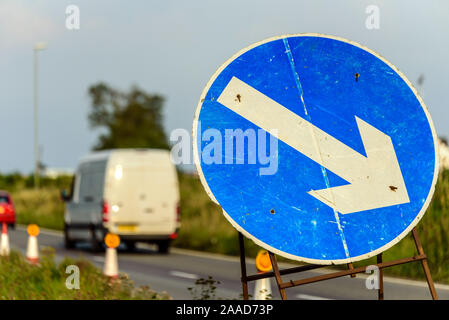 Roadworks freccia direzionale segno sul Regno Unito autostrada alla sera con il traffico passante Foto Stock