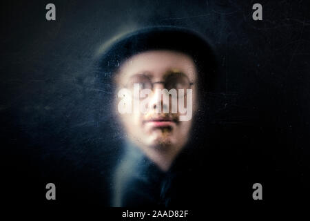 Mistero figura dietro un polveroso vetro graffiato Foto Stock