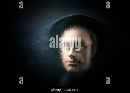 Mistero figura dietro un polveroso vetro graffiato Foto Stock
