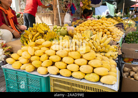 Mature Carabao Manghi e banane in vendita entro il mercato degli agricoltori a Cebu City, Filippine Foto Stock