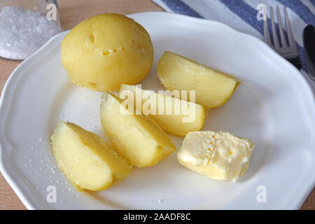 Patate cotte con burro e sale da pranzo o cena sulla piastra bianca. Cose-up Foto Stock