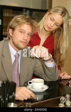 Junger Mann raucht im Restaurant, Frau schaut zu Foto Stock