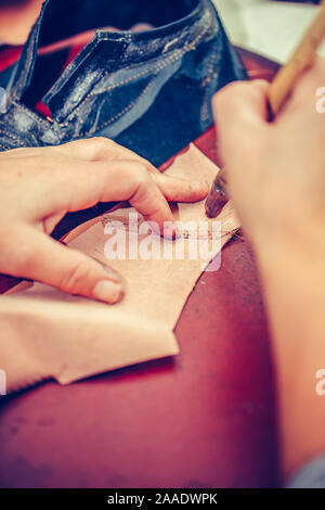 Le mani di un lavoratore con esperienza nelle calzature artigianali industria, eseguire solo operazioni di incollaggio, mettendo la colla sulle parti della calzatura. Messa a fuoco selettiva Foto Stock