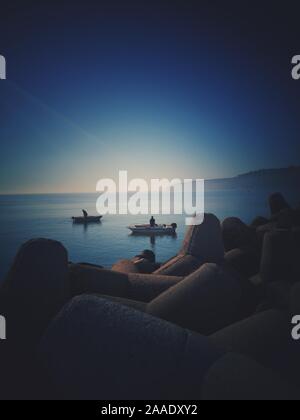 Barca da pesca e il pescatore in mare nel bel mattino. Golden sea sunrise. Foto Stock