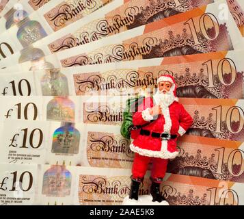 Un babbo natale figurina in piedi di fronte ad alcuni nuovi dieci pound notes.England Regno Unito Foto Stock