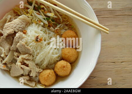 Vermicelli di riso topping sfera di gamberetti e slice bollito di maiale in zuppa mangiare da chopstick in legno Foto Stock