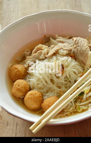 Vermicelli di riso topping sfera di gamberetti e slice bollito di maiale in zuppa mangiare da chopstick in legno Foto Stock