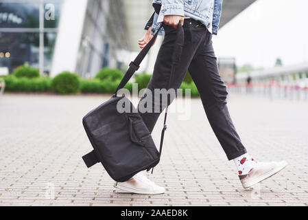 Giovane uomo bello con un sacchetto sulla sua spalla in fretta all'aeroporto Foto Stock