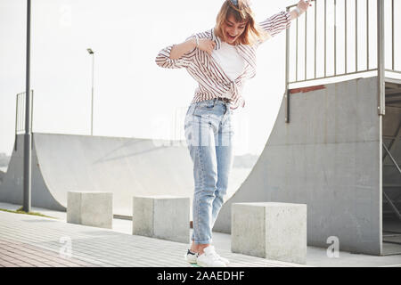 Una giovane donna sportiva che corre in un parco su uno skateboard. Foto Stock