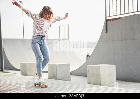 Una giovane donna sportiva che corre in un parco su uno skateboard. Foto Stock