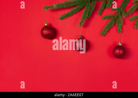 Bordo di Natale fatto di rami di abete e palle rosse. Natale sfondo rosso. Appartamento laico, vista dall'alto, copia dello spazio. Concetto di natale. Foto Stock