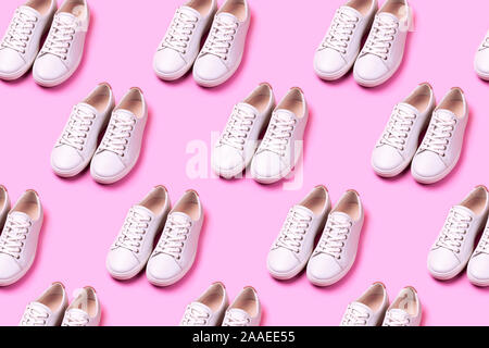 Modello realizzato di molti bianco sneakers trendy rosa su sfondo color pastello. Aprire la composizione. Piatto stile di laici. Foto Stock