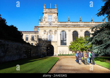 Un gruppo di visitatori in un tour guidato al Trinity College dell'università di Oxford, Inghilterra, stand su un percorso esterno la cappella su una soleggiata giornata invernale. Foto Stock