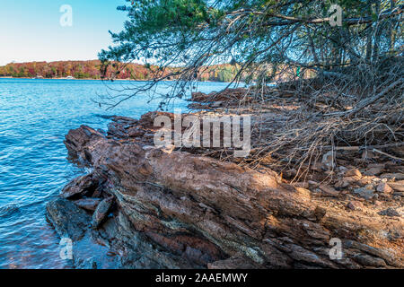 Una colorata rock formazione presso il punto della riva al Lago Lanier, Georgia con colore di autunno alberi in background su un luminoso giorno di sole in fal Foto Stock