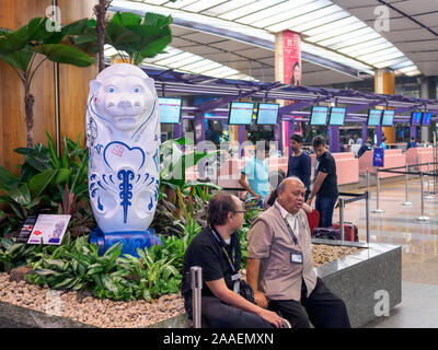 SINGAPORE - 4 ott 2019 - una bianca statua Merlion presso la sala partenze dell'Aeroporto Changi di Singapore, Terminal 1 con banchi per il check-in in background. Foto Stock