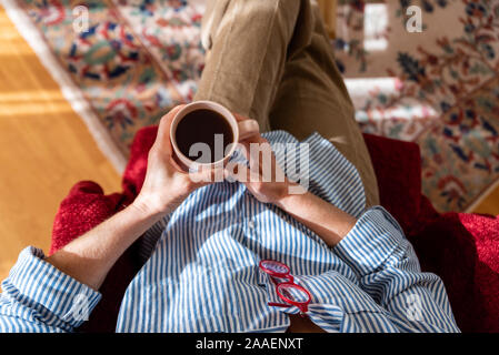 Le mani della donna matura azienda tazza di caffè, vista dall'alto Foto Stock