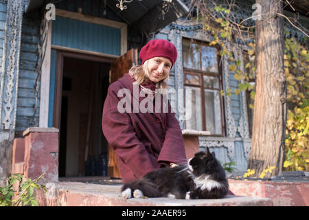Donna in autunno vestiti giocando con un gatto sotto il portico di un vintage country house. Foto Stock