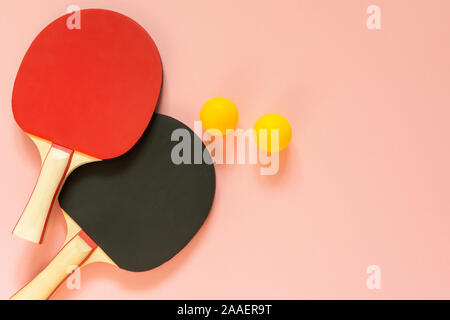 Nero e rosso tennis ping pong racchette e palline arancioni isolati su uno sfondo rosa, attrezzature sportive per il tennis da tavolo Foto Stock