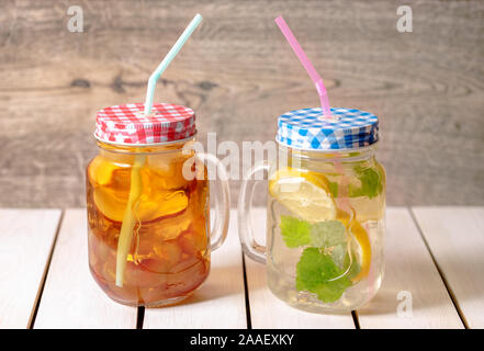 Limone, menta,apple e di mosti di uve detox in acqua di un muratore vasetto di vetro con paglia e fette contro un rustico sfondo di legno Foto Stock