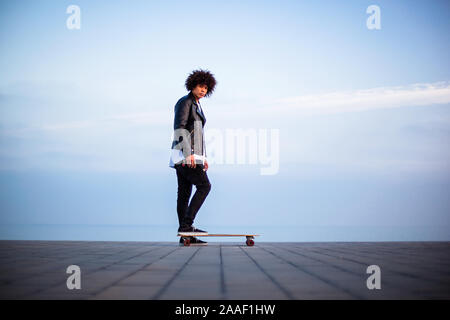 Bel giovane afro american ragazzo con lo skateboard con cielo blu, sfondo spazio copia Foto Stock