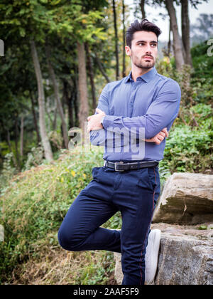Attraente giovane uomo in piedi in impostazione di natura da alberi Foto Stock