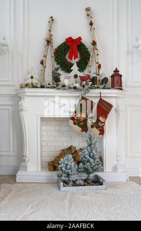 Decorate caminetto bianco per il Natale con piccoli alberi di Natale e calze Foto Stock