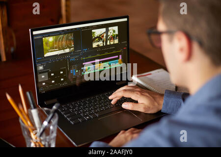Il freelance editor video lavora al computer portatile con Movie Editing Software. Videografo vlogger o blogger fotocamera uomo al lavoro modifica vlog Foto Stock
