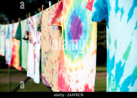 Una fila di colorati tie-dye T-shirt appesa fuori su uno stendibiancheria in sun Foto Stock