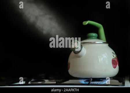 Il bollitore a caldo con acqua in ebollizione e il vapore fuoriesce da esso su sfondi scuri Foto Stock