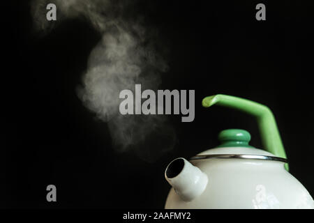 Il bollitore a caldo con acqua in ebollizione e il vapore fuoriesce da esso su sfondi scuri Foto Stock