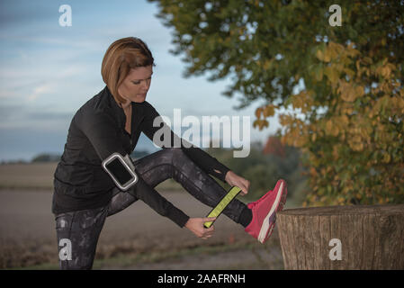 Giovane donna messa in sicurezza riflettore LED prima di fare jogging all'aperto Foto Stock