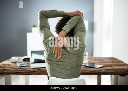 Vista posteriore di un imprenditore Stretching Braccia in Office Foto Stock