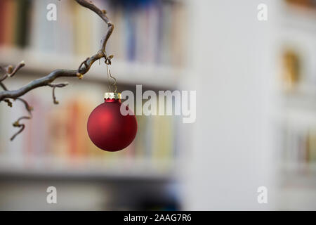 Close up di rosso palla di Natale presso una filiale di fronte unsharp sfondo di scaffale Foto Stock