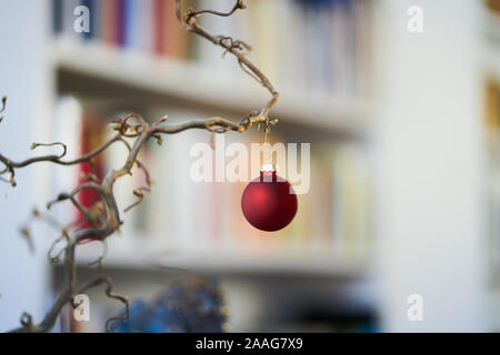 Close up di rosso palla di Natale presso una filiale di fronte unsharp sfondo di scaffale Foto Stock