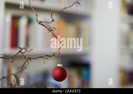 Close up di rosso palla di Natale presso una filiale di fronte unsharp sfondo di scaffale e mobili Foto Stock