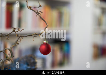 Close up di rosso palla di Natale presso una filiale di fronte unsharp sfondo di scaffale e mobili Foto Stock