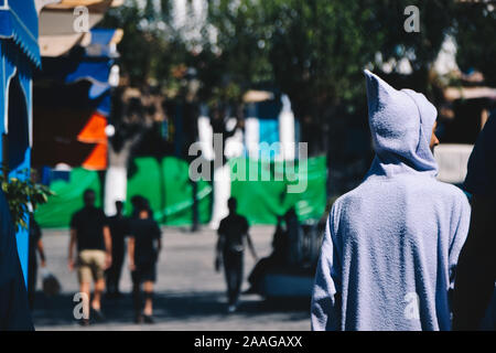 Uomini che camminano sulla strada indossando un cappotto blu con cofano Foto Stock