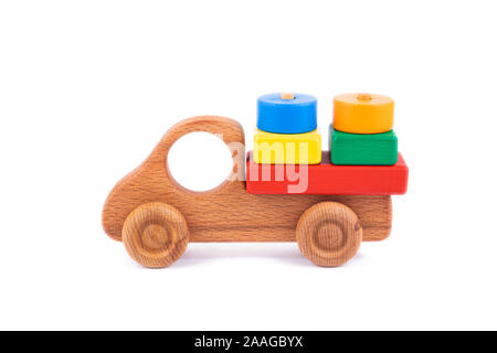 Close-up giocattolo per bambini è di legno naturale in forma di un autocarro con cassone ribaltabile con dei blocchi di legno sotto forma di multi-colore di forme geometriche su una bianca Foto Stock