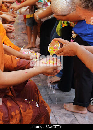 Durante il festival di Songkran, le persone partecipano a una cerimonia di versamento dell'acqua per i monaci per mostrare il loro rispetto. Foto Stock