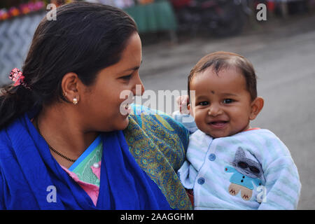 Carino baby boy con la madre guardando la telecamera sorridendo, Assam, India Foto Stock