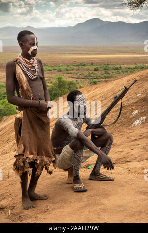 Etiopia, Sud Omo, Kolcho village, Karo tribal uomo con fucile bolt action, con la donna decorata con fango bianco, sopra il fiume Omo Foto Stock