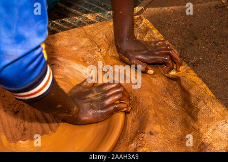 Etiopia, Sud Omo, Jinka, Yenegrew cucire Aari village, le mani del bambino potter rendendo injera piastra di cottura Foto Stock