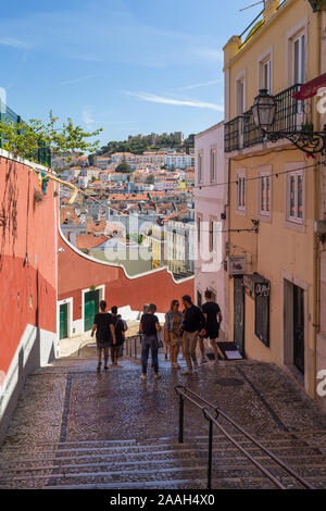 Persone a Calcada do Duque, ciottolosi strada pedonale che collega Bairro Alto e Rossio a Lisbona, Portogallo. Il castello Sao Jorge è in background Foto Stock