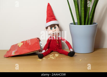 Elf Natale che si comportano male, mangiare tutti gli snack e patatine. Foto Stock